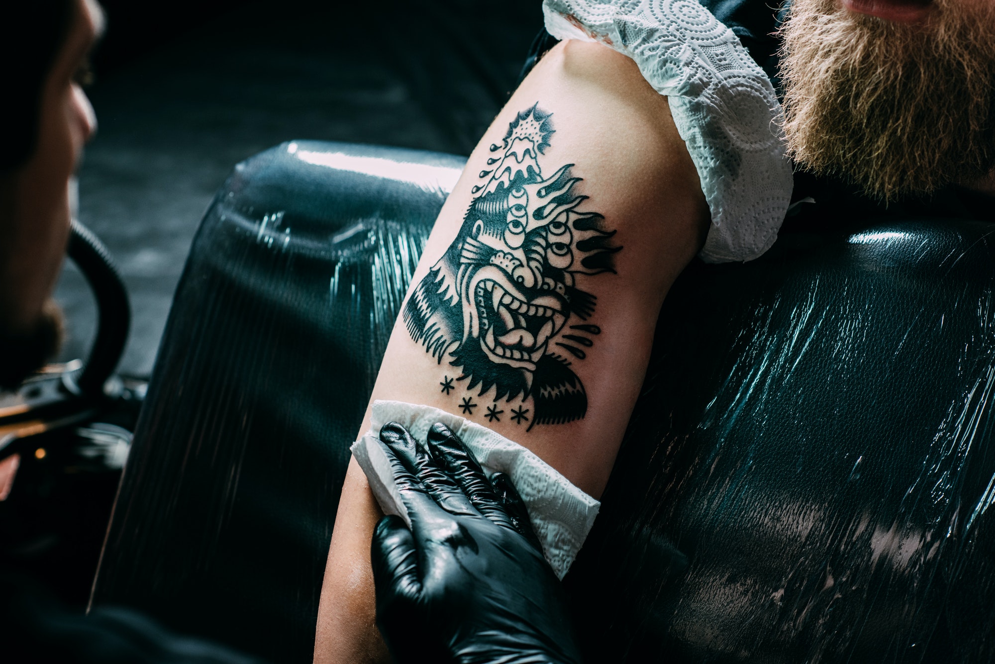 partial-view-of-tattoo-artist-in-gloves-working-on-tattoo-on-shoulder-in-salon.jpg